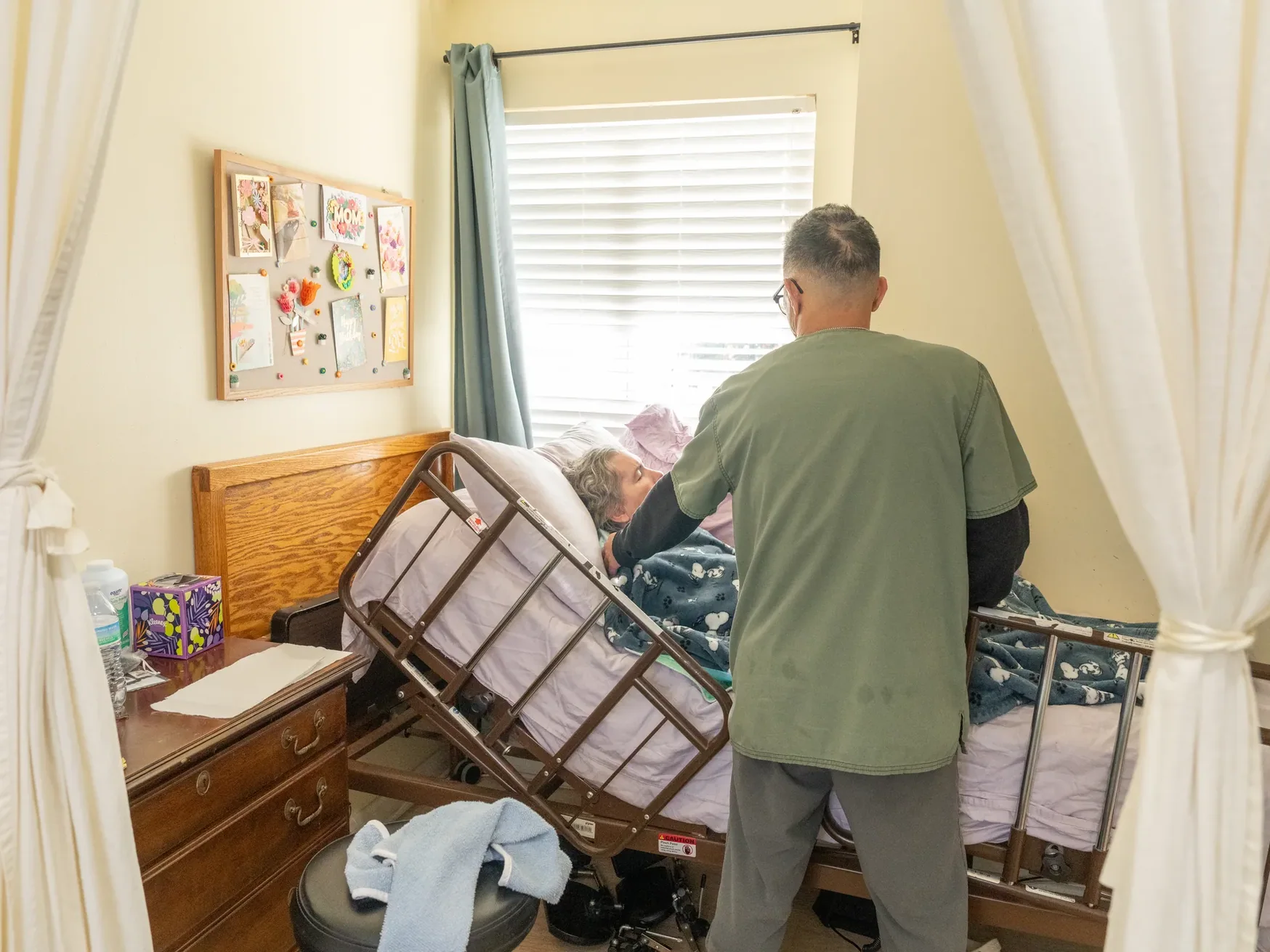 Caregiver attending to an elderly resident in their personal room